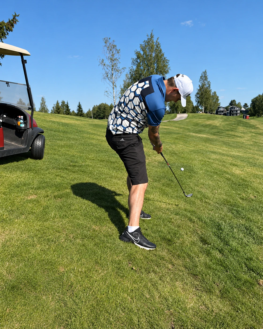 Sven Magne Hagen slår med jernkølle ved golfbilen